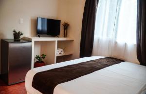 a bedroom with a bed and a tv and a window at C 33 Hospedaje Valladolid in Valladolid