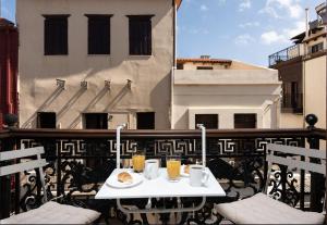 Ein Tisch mit zwei Tassen und einem Teller Essen auf einem Balkon in der Unterkunft Araldo in Chania