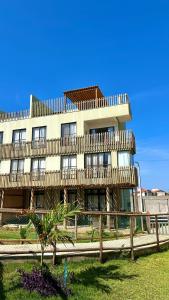 a large building with a wooden fence in front of it at Brisa Rooftop Vistamar -Apartamento à beira mar com jacuzzi in Luis Correia