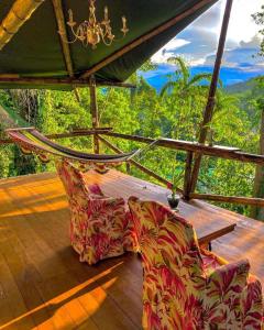 a couch on a deck with a view of the forest at Colina Secreta - Glamping and Villas in Puerto Viejo
