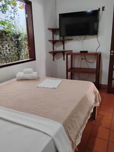 a bedroom with a bed and a flat screen tv at Pousada Barracuda Pipa in Pipa