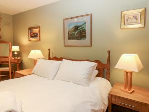 a bedroom with a bed with white pillows and two lamps at 1 The Cross in Dunkeld