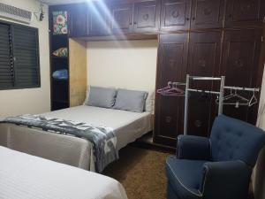 a bedroom with two beds and a chair and cabinets at Suite com ar in Jaú