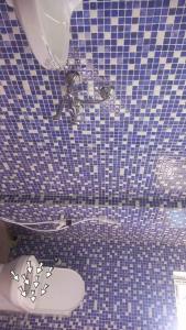 a bathroom with a blue tiled floor and a toilet at Devagram Guest house in Dergaon