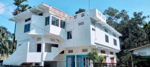 a white building with a sign on top of it at Devagram Guest house in Dergaon