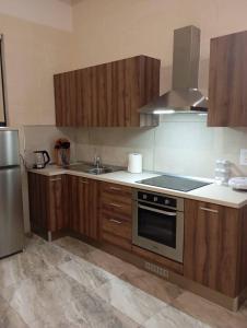 a kitchen with wooden cabinets and a stove top oven at NJ Stay Gozo in Għajnsielem