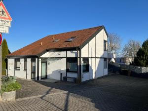 a white house with a brown roof on a street at Goodie Room I Apartment I Würzburg Estenfeld in Estenfeld