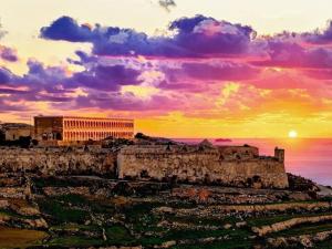 a sunset over the ruins of a building on a hill at NJ Stay Gozo in Għajnsielem