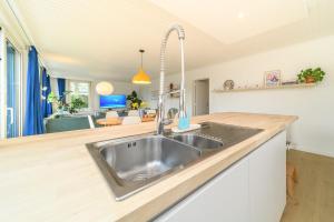 a kitchen with a stainless steel sink and a living room at Stormhus - Oostduinkerke in Koksijde +36 photos