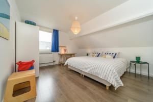 a white bedroom with a bed and a window at Stormhus - Oostduinkerke in Koksijde