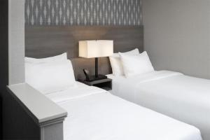 two white beds in a hotel room with a lamp at The Midtown Hotel MOD Collection by Sonesta in Boston +18 photos