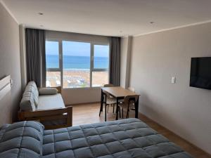 a bedroom with a bed and a table with a view of the ocean at MONOAMBIENTE EDIFICIO OCEANO NECOCHEA frente al mar, in Necochea
