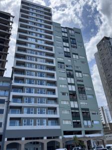 a tall apartment building with cars parked in front of it at MONOAMBIENTE EDIFICIO OCEANO NECOCHEA frente al mar, in Necochea