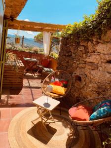 a patio with chairs and a table and a stone wall at Moulin Lombard B&B Chambre et table d Hôtes Massages & Bien-être in Les Arcs sur Argens