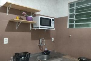 a microwave sitting on a shelf above a sink at Duque de Caxias Apartmento in Duque de Caxias