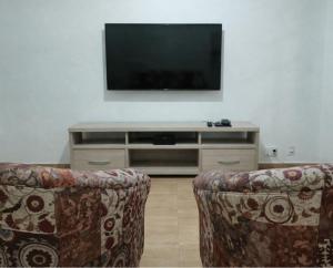 a living room with two chairs and a flat screen tv at Duque de Caxias Apartmento in Duque de Caxias