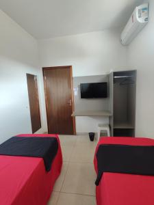 a room with two beds and a flat screen tv at Quarto Duplo Comercial - Queen's Hotel in Formosa