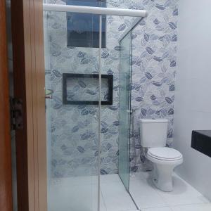 a bathroom with a toilet and a glass shower door at Descanso Paz e sossego com muito aconchego in Prado +10 photos