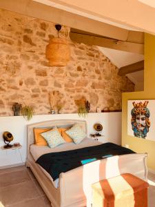 a bedroom with a bed with a stone wall at Moulin Lombard B&B Chambre et table d Hôtes Massages & Bien-être in Les Arcs sur Argens
