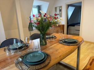 a wooden table with plates and a vase of flowers at Apartment am Ostorfer See in Schwerin +18 photos