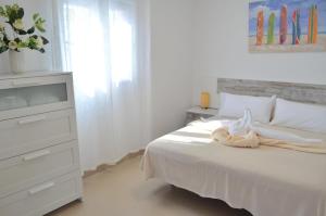 a white bedroom with a white bed and a dresser at Sand & Beach in Pájara