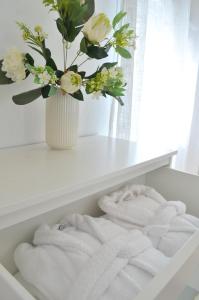 a white shelf with towels and a vase with flowers at Sand & Beach in Pájara