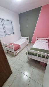 two beds in a room with pink and white walls at Casa Holambra Van den Broek in Holambra +9 photos
