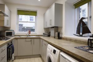 a kitchen with white cabinets and a washer at Converted Coastal Coach House in Weston-super-Mare