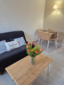 a living room with a vase of flowers on a coffee table at Centre Chartres Parking privé Climatiseur in Chartres