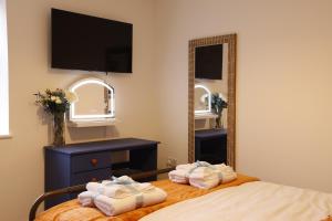a bedroom with towels on a bed and a mirror at Converted Coastal Coach House in Weston-super-Mare