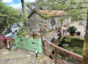a house with a wooden fence and a waterfall at Moinho de Brião in Montalegre