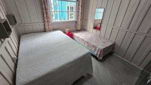 a small bedroom with two beds and a window at Casa da vó cida in Itapoa
