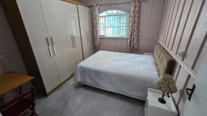 a small bedroom with a bed and a cabinet at Casa da vó cida in Itapoa