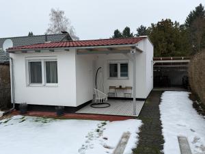 a white house with a deck in the snow at Avar Inn in Tiszalök