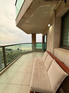 a balcony with a couch on top of a building at נוף ראשון לים in Ashkelon