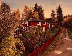 a red house with a fence next to a road at Villa nära Järvsö in Järvsö