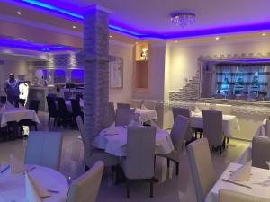 a restaurant with white tables and chairs and a bar at Hotel Restaurant Parthenon in Otterbach