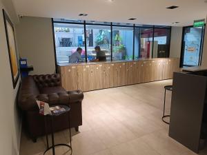 a waiting room with a leather couch in front of a counter at ANDÉN by FMA Coliving in Salta