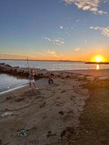 a woman swinging a pole on the beach at sunset at Kata in Privlaka