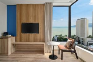 a living room with a tv and a chair and a table at Four Points by Sheraton Nha Trang in Nha Trang