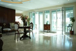 a living room with a table and chairs and windows at Holyland Hotel Amman in Amman