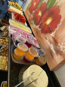 a buffet of food with jars of juice and a painting at HOTEL PLAZA PONTES e LACERDA in Pontes e Lacerda