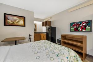 a small bedroom with a bed and a kitchen at HomeTowne Studios by Red Roof Buffalo - Niagara Airport in Williamsville