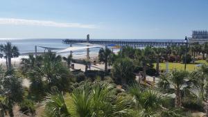 a view of a beach with a pier and palm trees at Admiral Motor Inn in Myrtle Beach