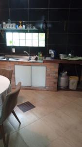 a kitchen with a sink and a counter with a table at Chalé da Janete in Capão da Canoa