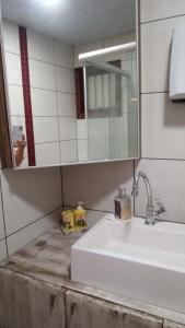 a bathroom with a white sink and a mirror at Chalé da Janete in Capão da Canoa