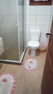 a bathroom with a toilet and a glass shower at Chalé da Janete in Capão da Canoa
