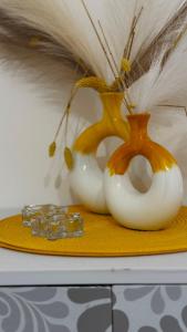 three white vases on a yellow plate with crystals at Lumèra Holiday Home in Pizzo