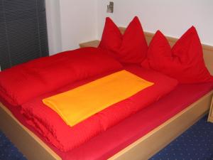 a bed with red and yellow pillows on it at Appartement Granbichler Siegfried in Längenfeld