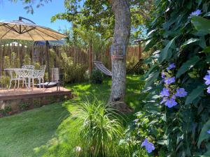 a garden with a tree and a swing and blue flowers at Chalé Makar - Hidromassagem aquecida e vista para as montanhas in Serra do Cipo